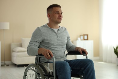 Photo of Young man in modern wheelchair at home