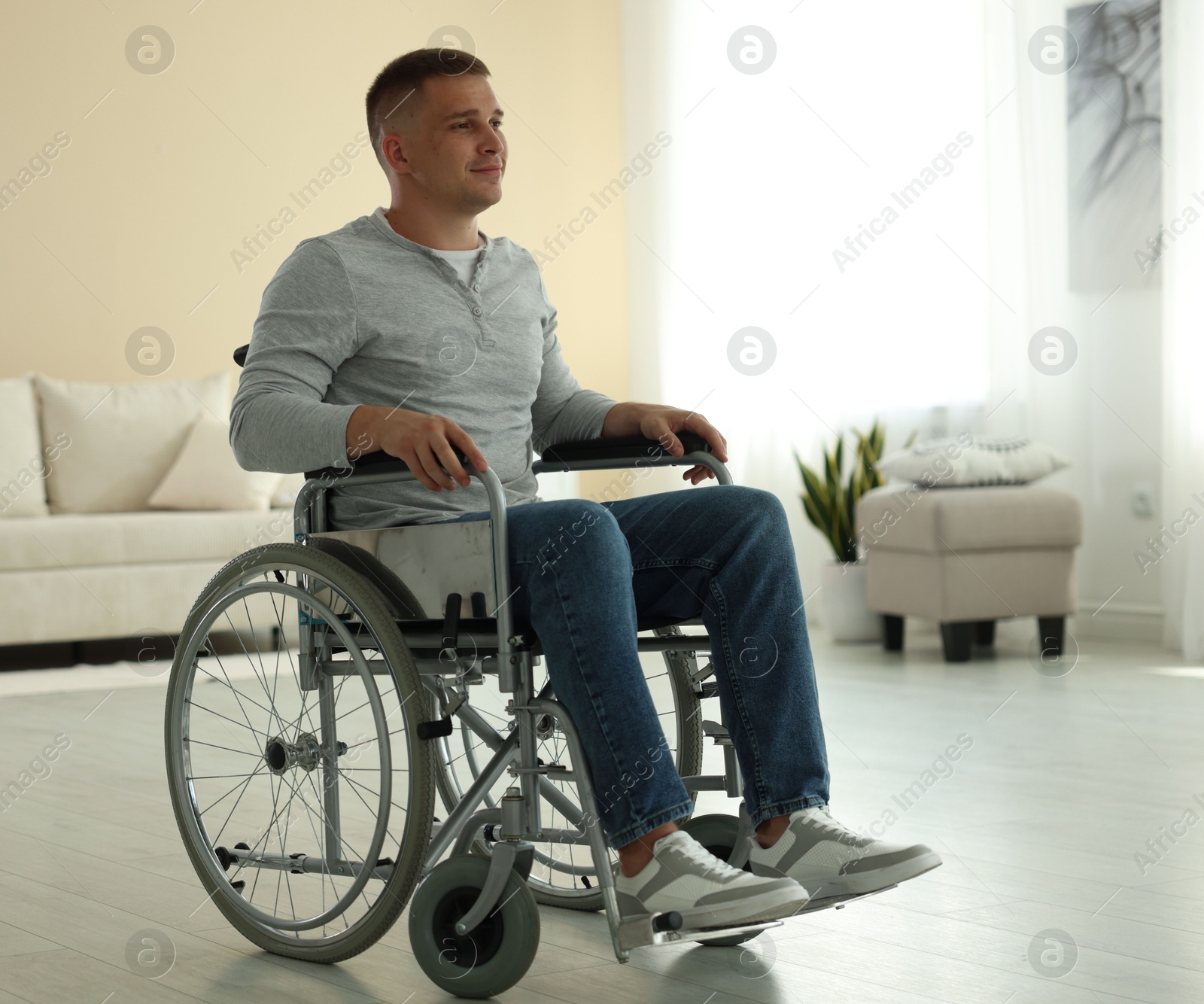 Photo of Young man in modern wheelchair at home
