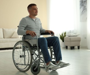 Photo of Young man in modern wheelchair at home