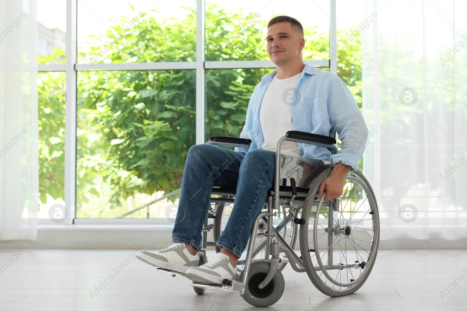 Young man in wheelchair near window indoors Photo of Young man in wheelchair near window indoors