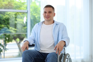 Photo of Young man in wheelchair near window indoors