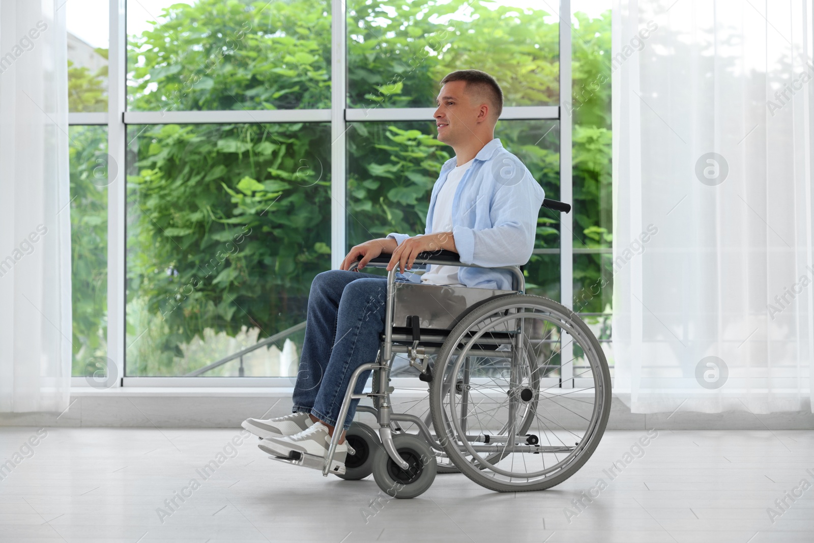 Young man in wheelchair near window indoors Photo of Young man in wheelchair near window indoors