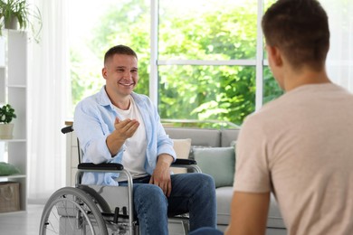 Photo of Man in wheelchair talking with caregiver indoors