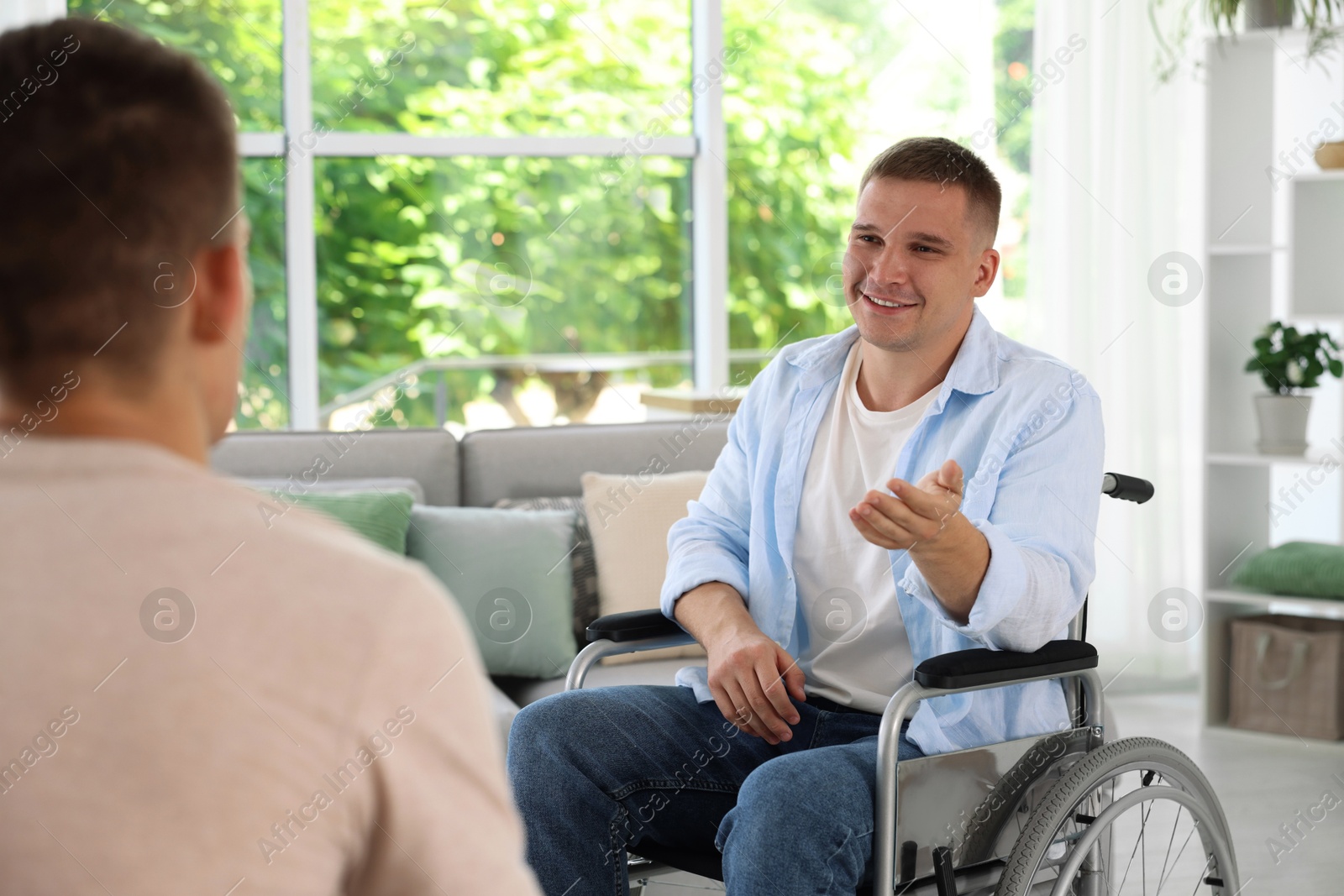 Photo of Man in wheelchair talking with caregiver indoors