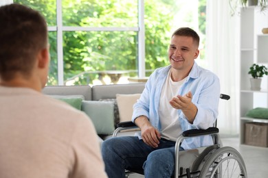 Photo of Man in wheelchair talking with caregiver indoors