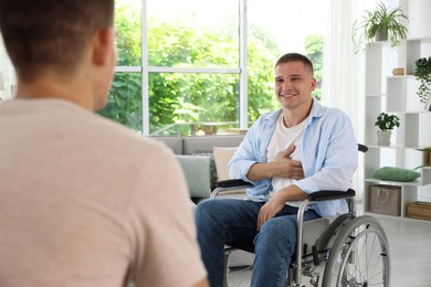 Photo of Man in wheelchair talking with caregiver indoors