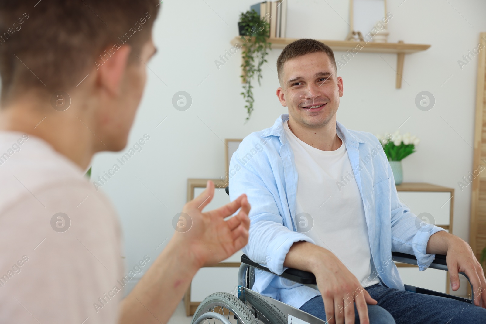 Photo of Man in wheelchair talking with caregiver indoors