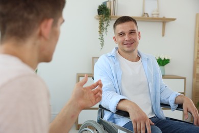 Photo of Man in wheelchair talking with caregiver indoors