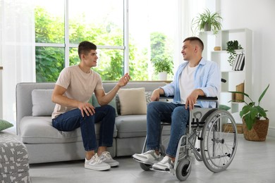 Photo of Man in wheelchair talking with caregiver indoors