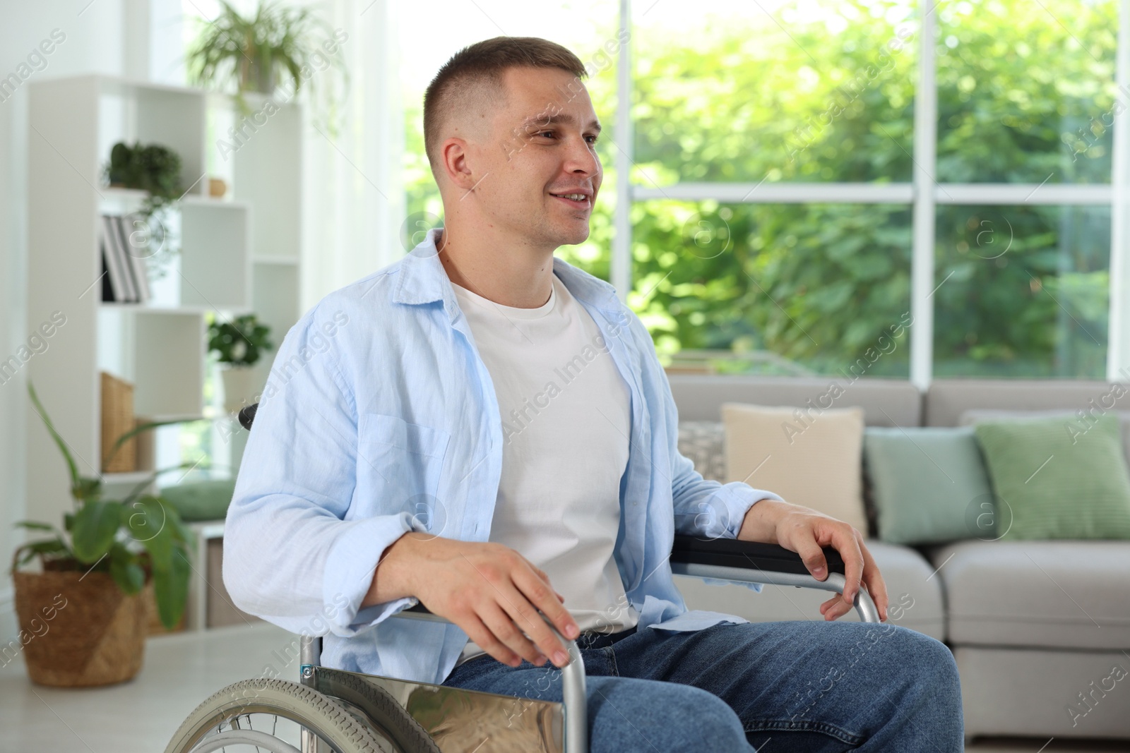 Photo of Young man in modern wheelchair at home