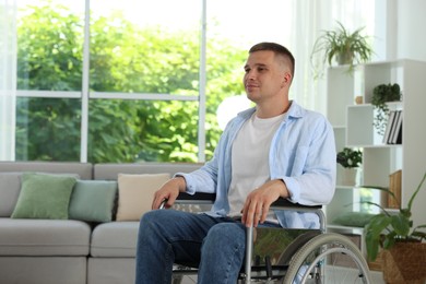 Photo of Young man in modern wheelchair at home
