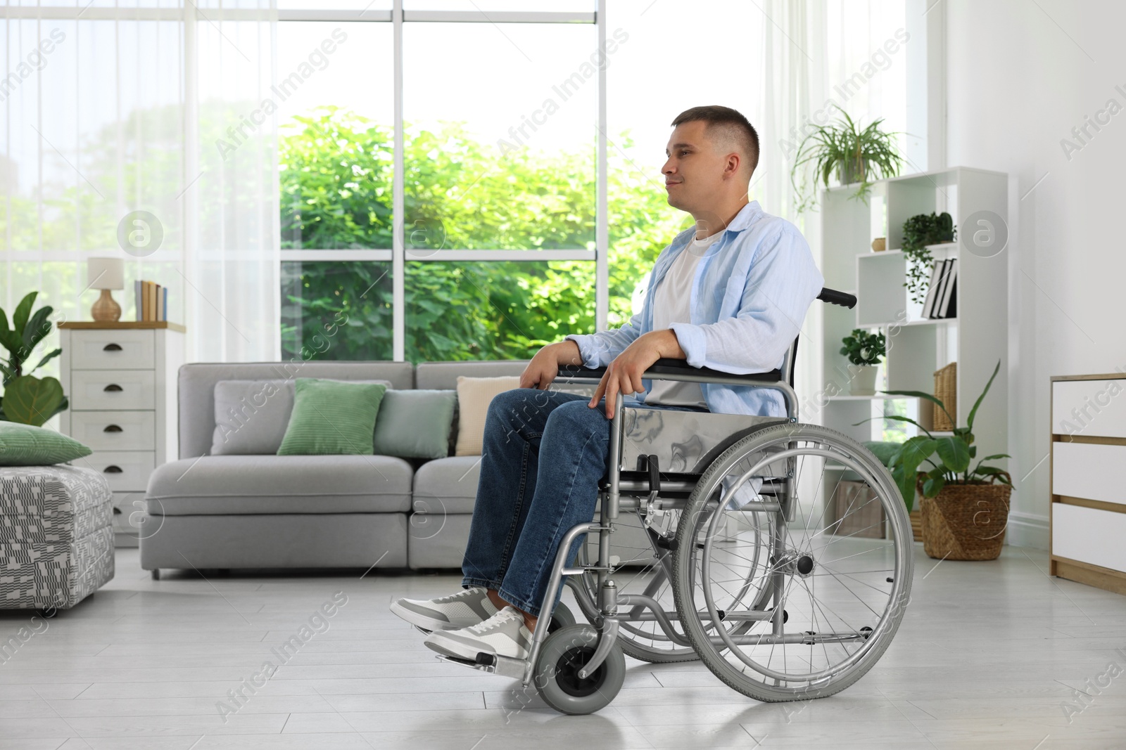 Photo of Young man in modern wheelchair at home