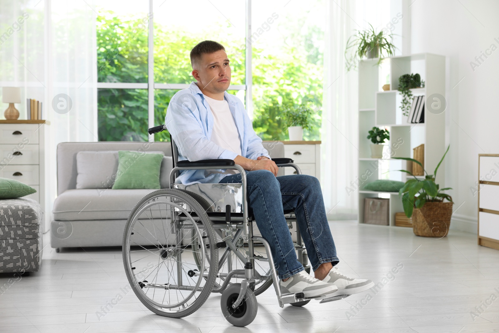 Photo of Young man in modern wheelchair at home