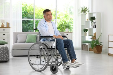 Photo of Young man in modern wheelchair at home