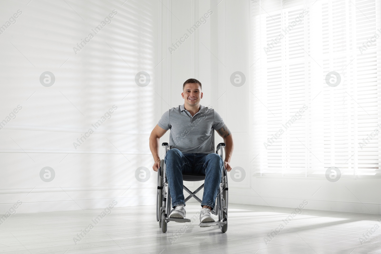 Photo of Young man in modern wheelchair at home