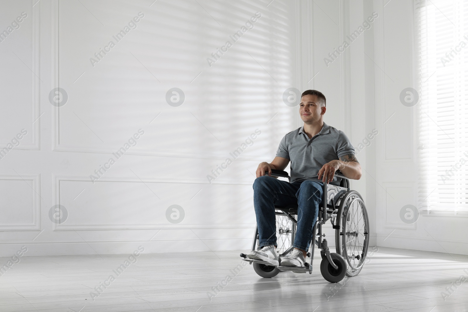 Photo of Young man in wheelchair at home, space for text