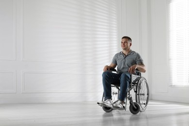 Photo of Young man in wheelchair at home, space for text