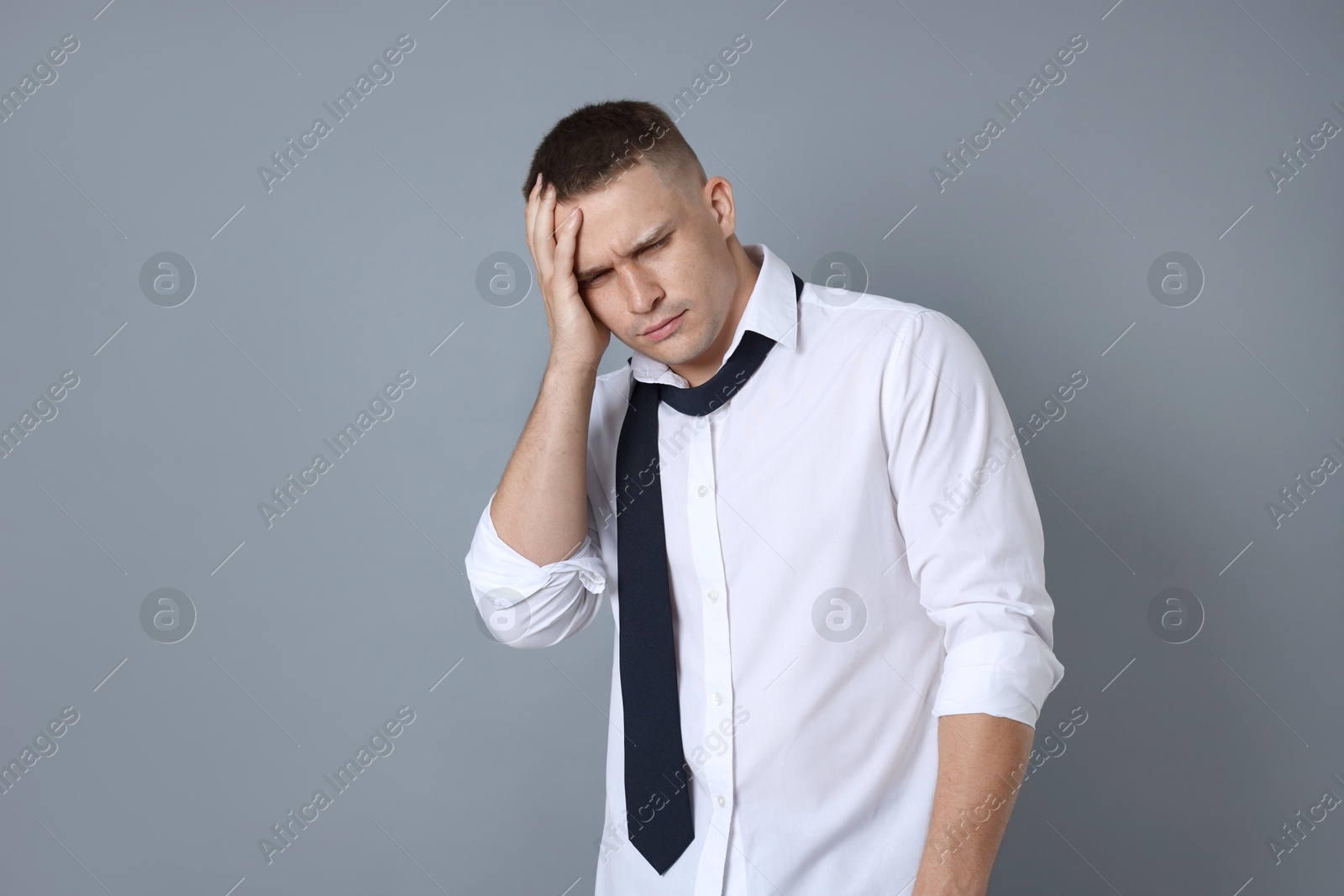Man suffering from hangover on grey background Photo of Man suffering from hangover on grey background