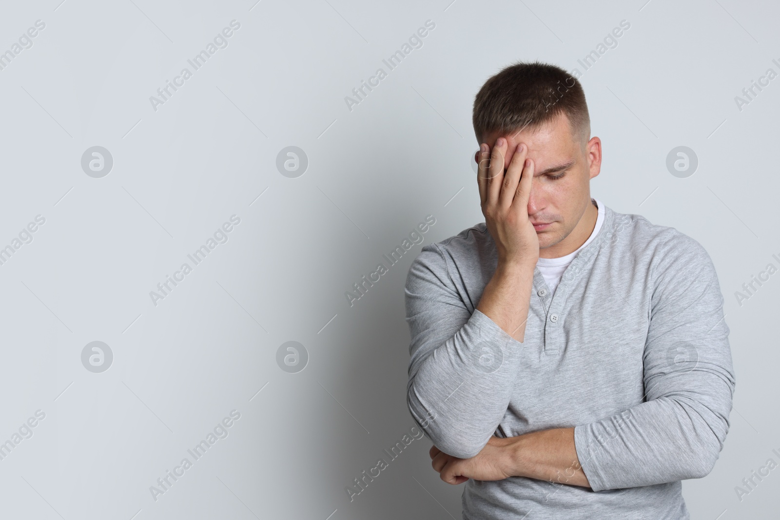 Photo of Man suffering from hangover on light grey background, space for text