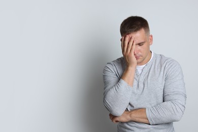 Photo of Man suffering from hangover on light grey background, space for text
