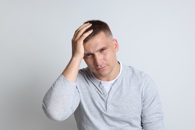 Photo of Man suffering from hangover on light grey background