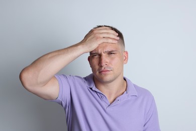 Photo of Man suffering from hangover on light grey background