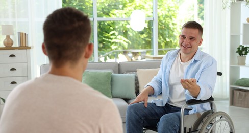 Photo of Man in wheelchair talking with caregiver indoors