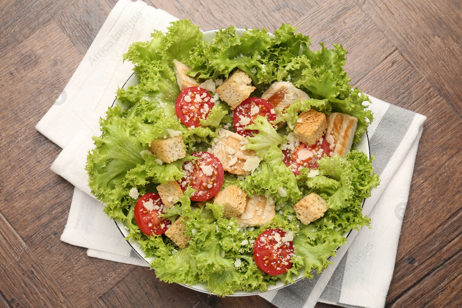 Photo of Tasty salad with croutons, tomatoes, cheese and chicken on wooden table, top view
