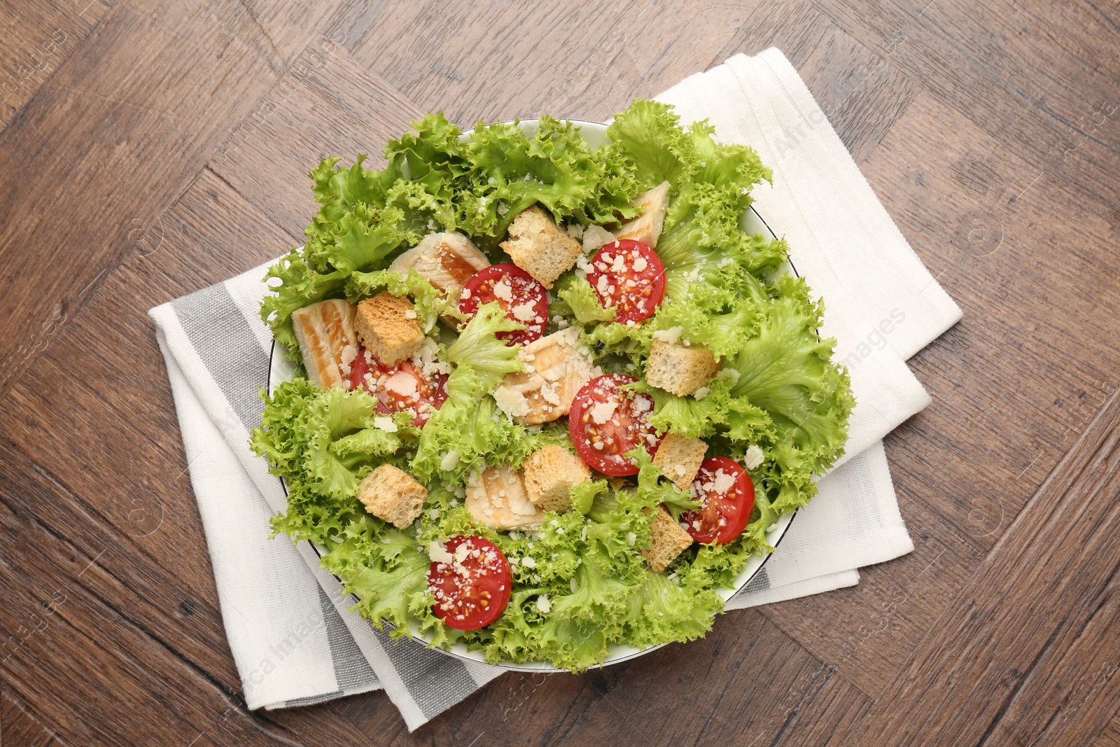 Photo of Tasty salad with croutons, tomatoes, cheese and chicken on wooden table, top view