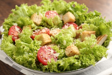 Photo of Tasty salad with croutons, tomatoes, cheese and chicken on wooden table, closeup