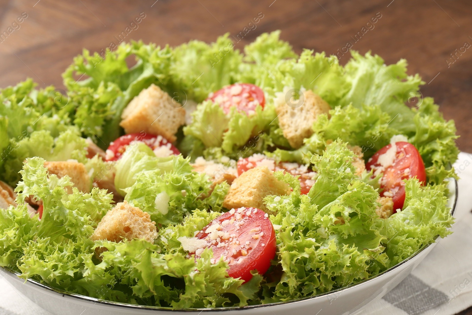 Photo of Tasty salad with croutons, tomatoes, cheese and chicken on wooden table, closeup