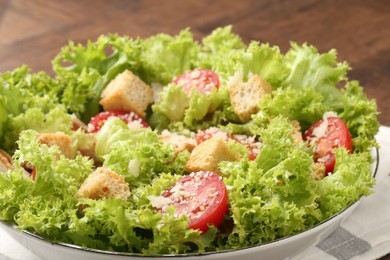 Photo of Tasty salad with croutons, tomatoes, cheese and chicken on wooden table, closeup