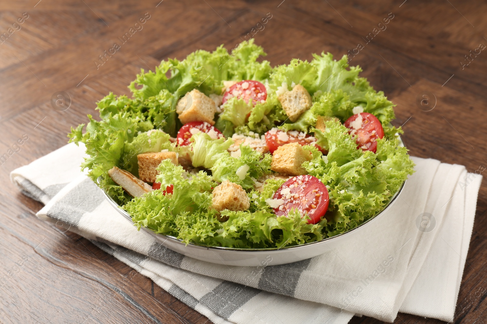 Photo of Tasty salad with croutons, tomatoes, cheese and chicken on wooden table, closeup