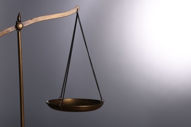 Photo of Scales of justice against grey background, closeup. Space for text
