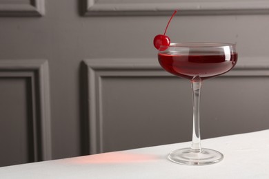 Photo of Tasty cherry cocktail on white table, closeup. Space for text