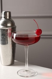 Photo of Tasty cherry cocktail and shaker on white table, closeup