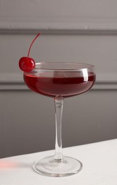 Photo of Tasty cherry cocktail on white table, closeup