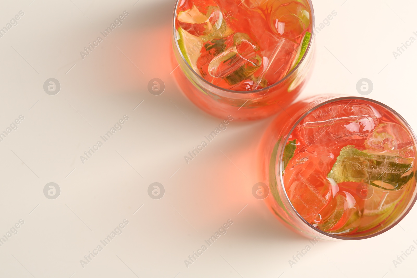 Tasty cocktail with ice cubes and lime on white table, top view. Space for text Photo of Tasty cocktail with ice cubes and lime on white table, top view. Space for text