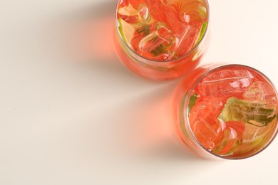 Photo of Tasty cocktail with ice cubes and lime on white table, top view. Space for text