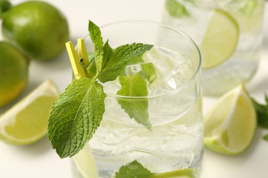 Photo of Tasty cocktail with lime and ice cubes on white table, closeup