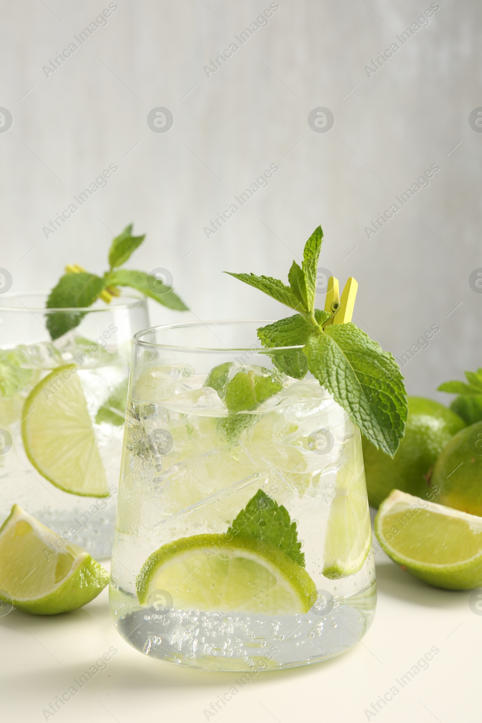 Tasty cocktail with lime and ice cubes on white table, closeup Photo of Tasty cocktail with lime and ice cubes on white table, closeup