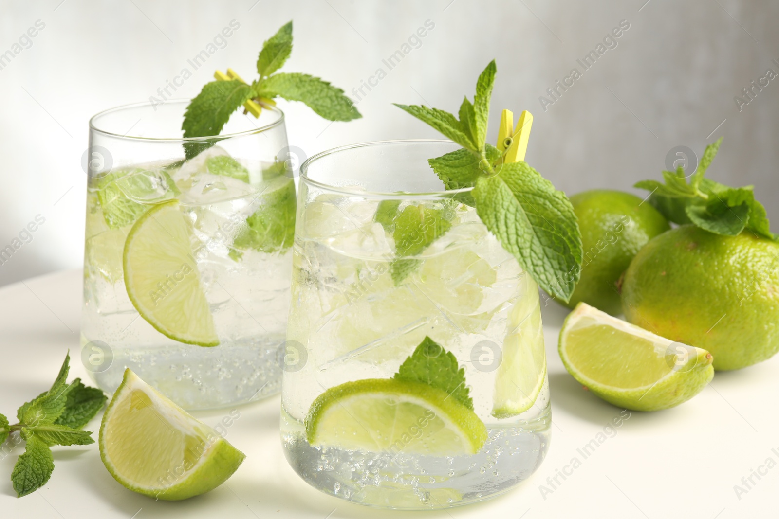 Tasty cocktail with lime and ice cubes on white table, closeup Photo of Tasty cocktail with lime and ice cubes on white table, closeup