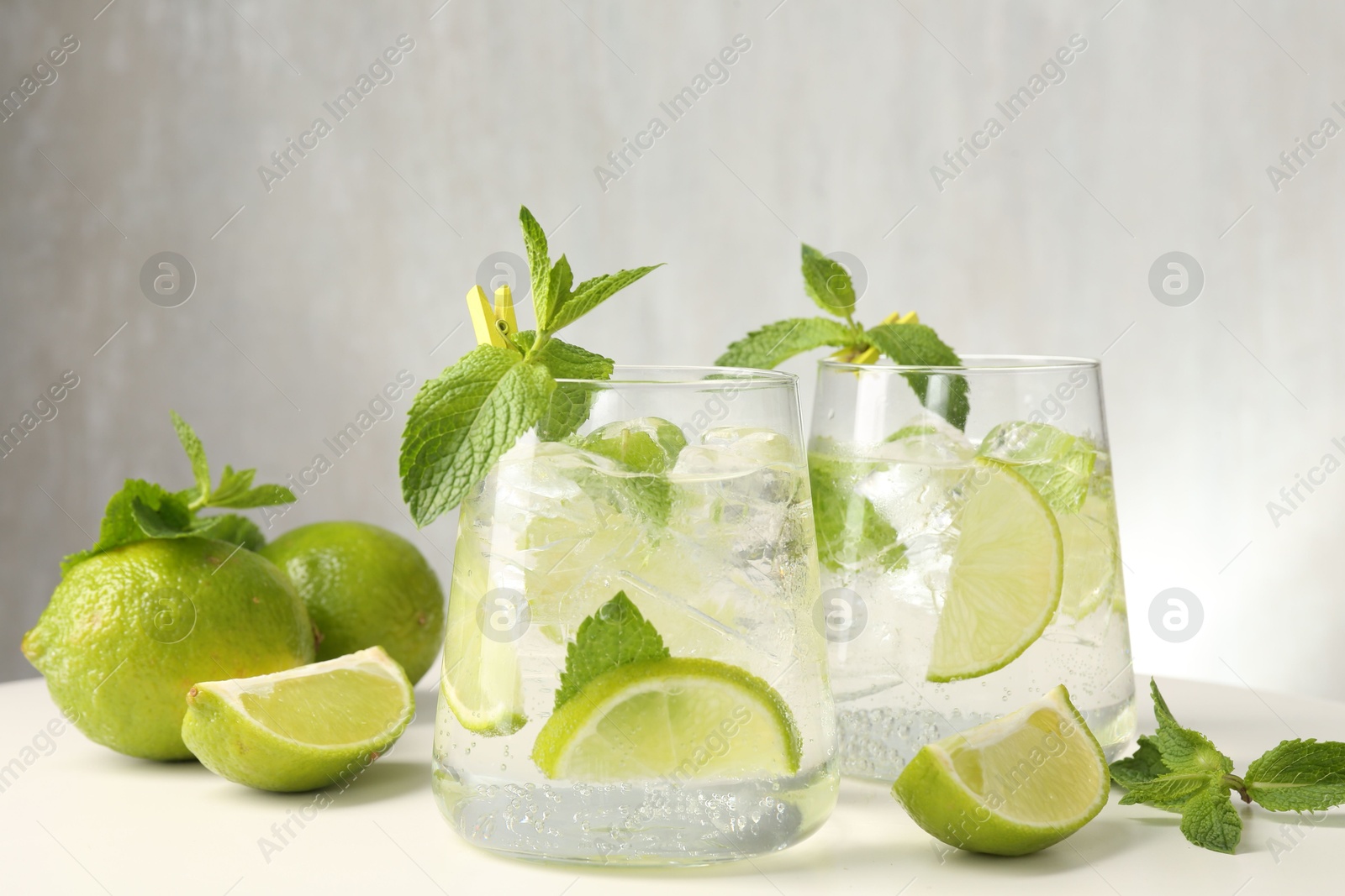 Tasty cocktail with lime and ice cubes on white table, closeup Photo of Tasty cocktail with lime and ice cubes on white table, closeup