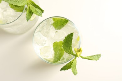Photo of Tasty cocktail with lime and ice cubes on white table, flat lay
