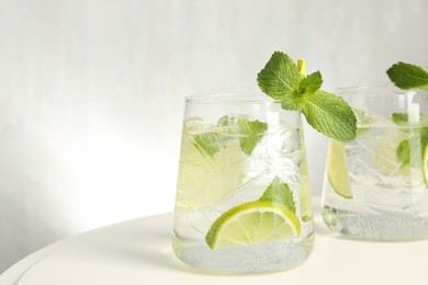 Photo of Tasty cocktail with lime and ice cubes on white table, closeup. Space for text