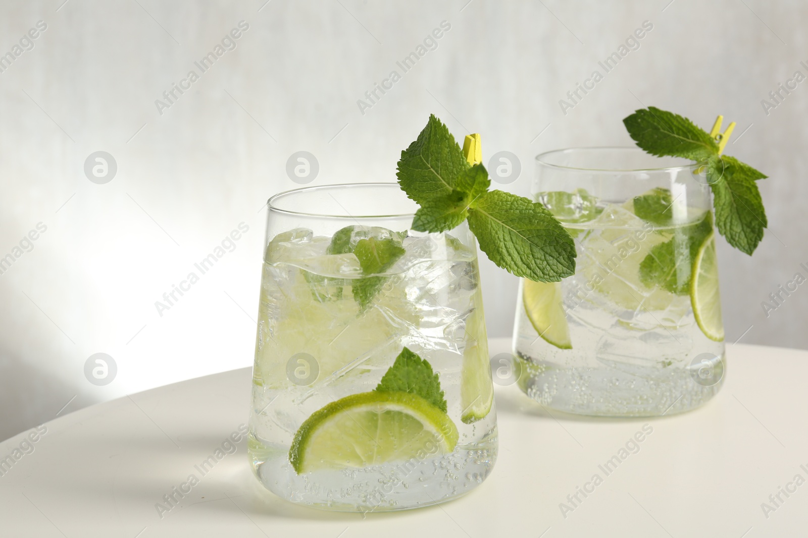 Tasty cocktail with lime and ice cubes on white table, closeup Photo of Tasty cocktail with lime and ice cubes on white table, closeup