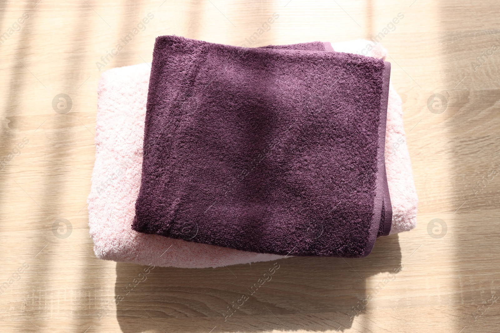 Photo of Stack of soft towels on wooden table, above view
