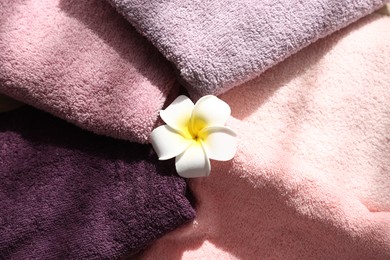 Photo of Soft towels and plumeria flower as background, top view