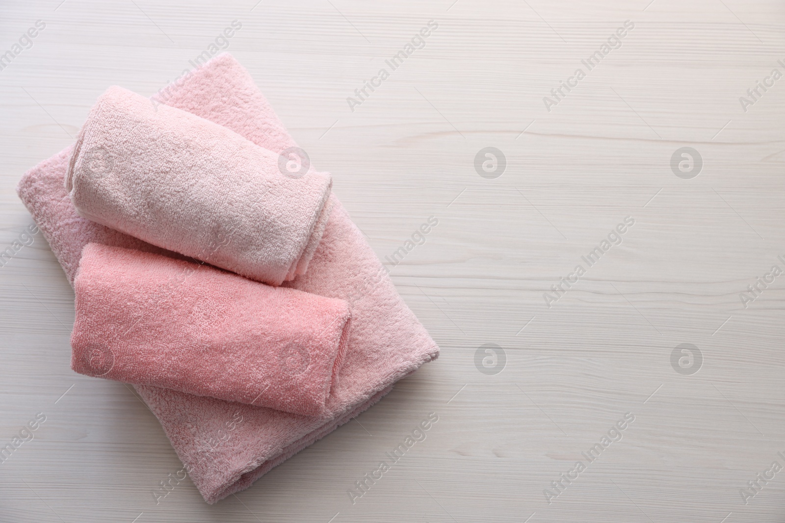 Photo of Pink towels on light wooden table, top view. Space for text