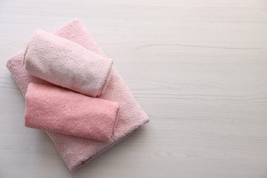 Photo of Pink towels on light wooden table, top view. Space for text